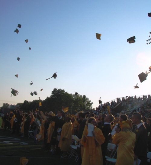 The graduates celebrate by throwing their hats in the air!